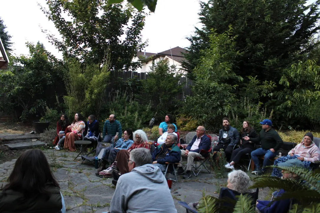 Outdoor gathering with people seated in chairs.
