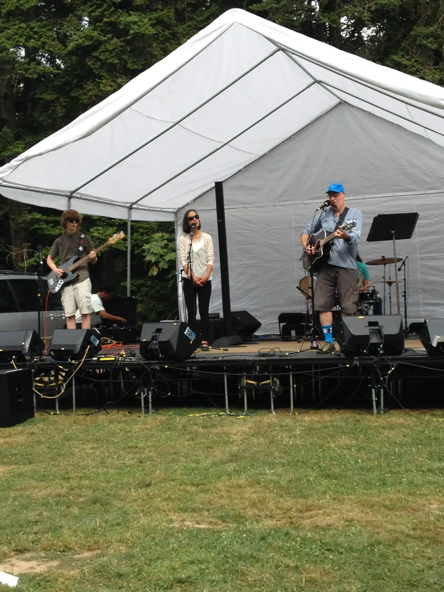 Band performing on outdoor stage under tent.