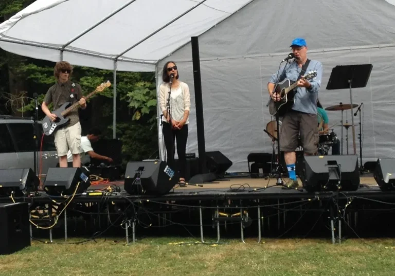 Band performing on outdoor stage under tent.