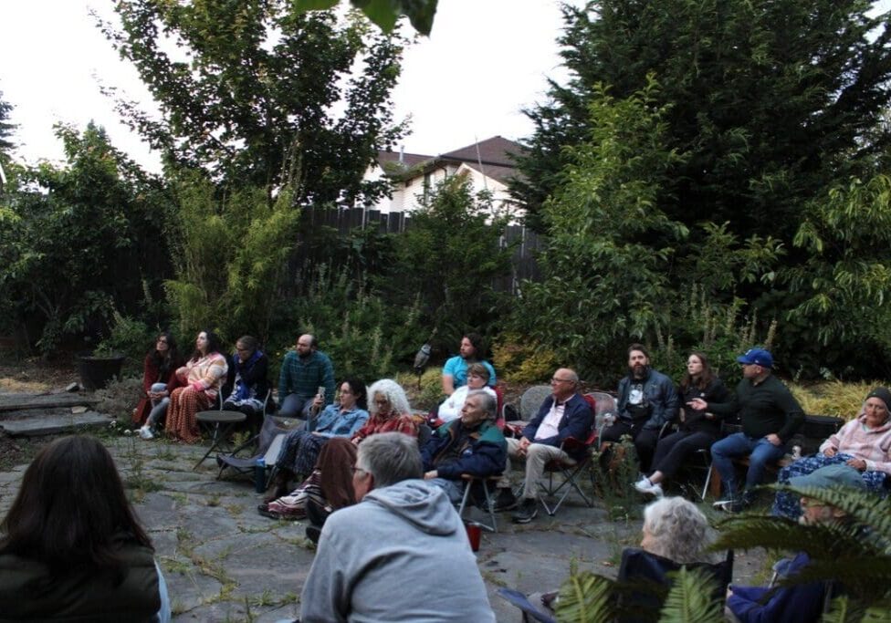 Outdoor gathering with people seated in chairs.